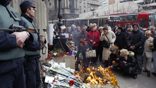 Naoružani policajci čuvaju glavni ulaz u zgradu Vlade Srbije dok ljudi pale sveće u znak počasti ubijenom premijeru Srbije Zoranu Đinđiću u Beogradu 13. marta 2003. (Foto REUTERS/Petar Kujundžić)
